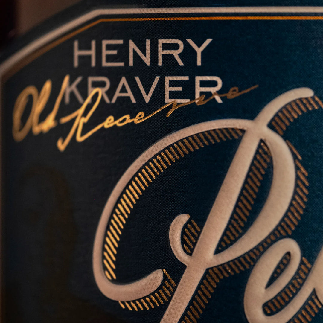 Henry Kraver product label showcasing a dark teal textured background with white sans-serif text, elegant gold foil script Old Reserve, and a large embossed cream Reserve lettered with intricate gold dashed details