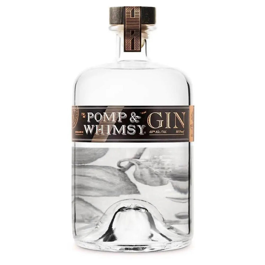 A clear glass bottle of Pomp & Whimsy Gin featuring a black and gold label, a distinctive wooden cork with a patterned gold top, and subtle floral artwork visible through the liquid