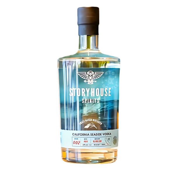 Photograph of a Storyhouse Spirits California Seaside Vodka bottle featuring a blue-green label with an ocean wave design and white owl logo, containing clear liquid with a subtle golden hue and capped with black